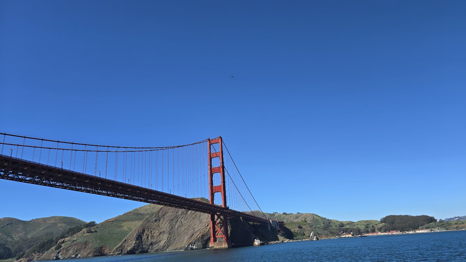 The Golden Gate Bridge on a clear, fog-free day with green Marin hills in the background
